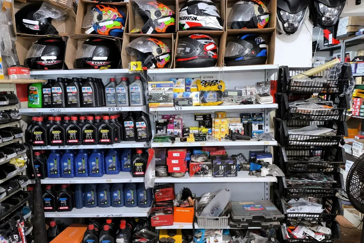 Prateleiras da loja com capacetes, óleos de motor e baterias